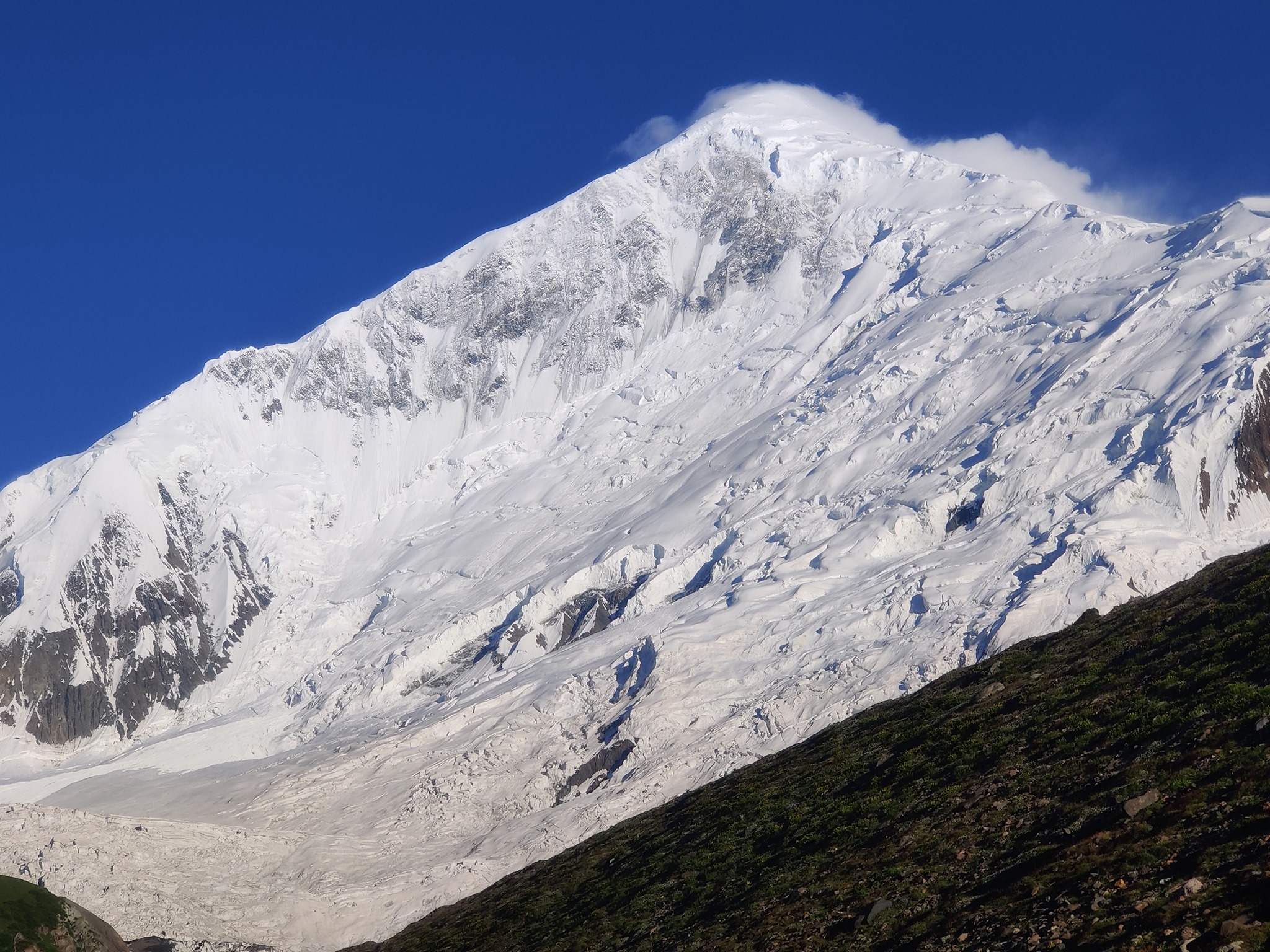 пик Диран (Diran Peak, 7266 метров), белая пирамида, возвышающаяся над зелеными лугами. Фотография: Helias Millerioux